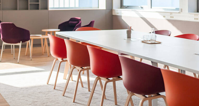 Salle de réunion aux Laboratoires Boiron, équipée de tables et de chaises confortables pour les réunions formelles, avec un espace additionnel comprenant des fauteuils pour des discussions informelles.