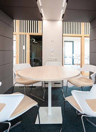 Table entourée de cinq chaises dans une cabine acoustique de l'ATMB, créant un espace de réunion privé et confortable pour les discussions en petit comité.