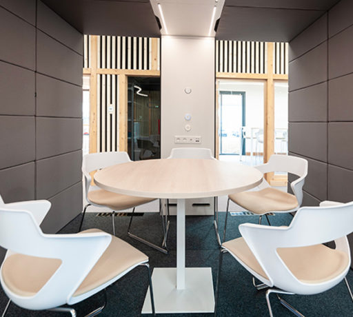 Table entourée de cinq chaises dans une cabine acoustique de l'ATMB, créant un espace de réunion privé et confortable pour les discussions en petit comité.