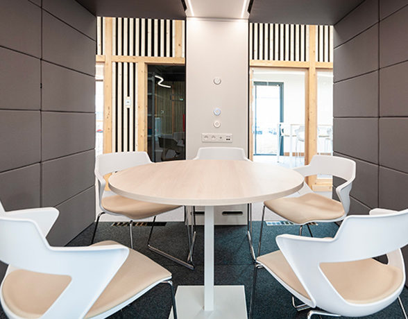 Table entourée de cinq chaises dans une cabine acoustique de l'ATMB, créant un espace de réunion privé et confortable pour les discussions en petit comité.