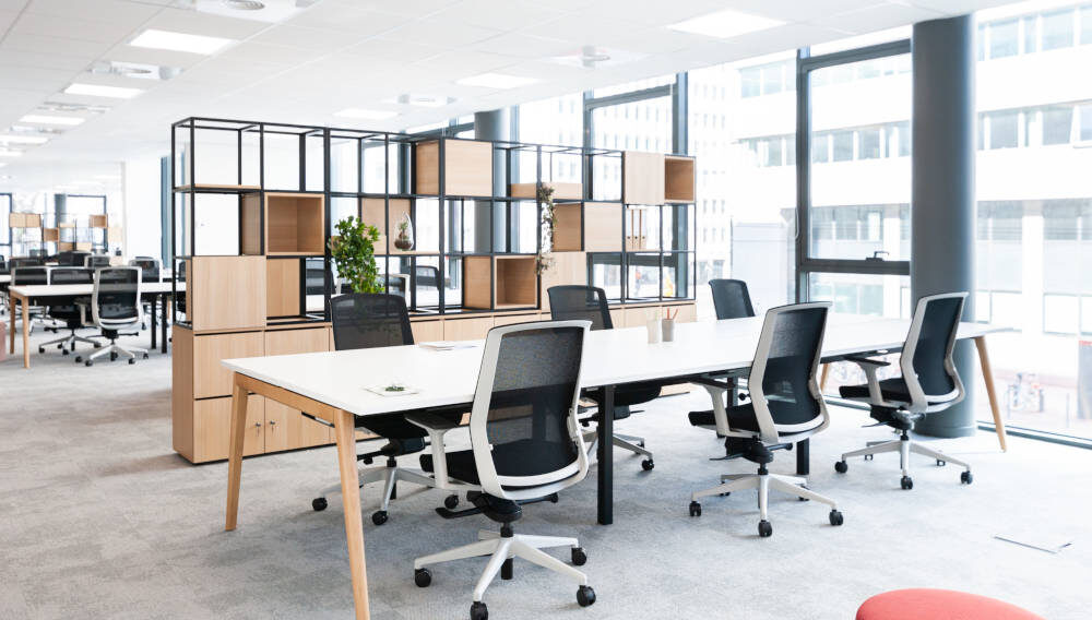 Bureau ouvert équipé de tables Woodesk et de sièges ergonomiques J1 avec un séparateur CORRAL, créant un espace de travail à la fois fonctionnel et ergonomique pour un confort optimal tout au long de la journée.