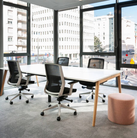 Bureau équipé d'une table Woodesk accompagnée de quatre sièges ergonomiques J1 et d'un pouf, offrant un espace de travail fonctionnel et confortable pour des sessions prolongées.