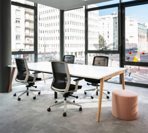 Bureau équipé d'une table Woodesk accompagnée de quatre sièges ergonomiques J1 et d'un pouf, offrant un espace de travail fonctionnel et confortable pour des sessions prolongées.