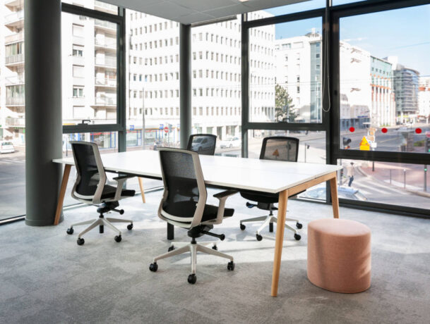 Bureau équipé d'une table Woodesk accompagnée de quatre sièges ergonomiques J1 et d'un pouf, offrant un espace de travail fonctionnel et confortable pour des sessions prolongées.