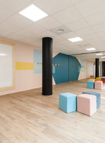 Salle de créativité aménagée avec des porte-manteaux Fixil, des poufs confortables et un tableau, offrant un espace inspirant et fonctionnel pour des sessions de brainstorming.