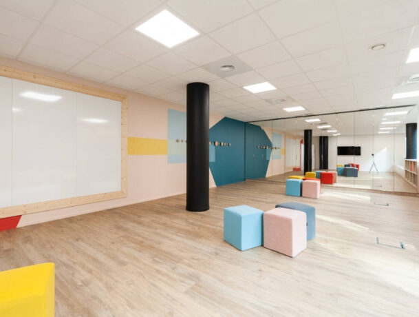 Salle de créativité aménagée avec des porte-manteaux Fixil, des poufs confortables et un tableau, offrant un espace inspirant et fonctionnel pour des sessions de brainstorming.