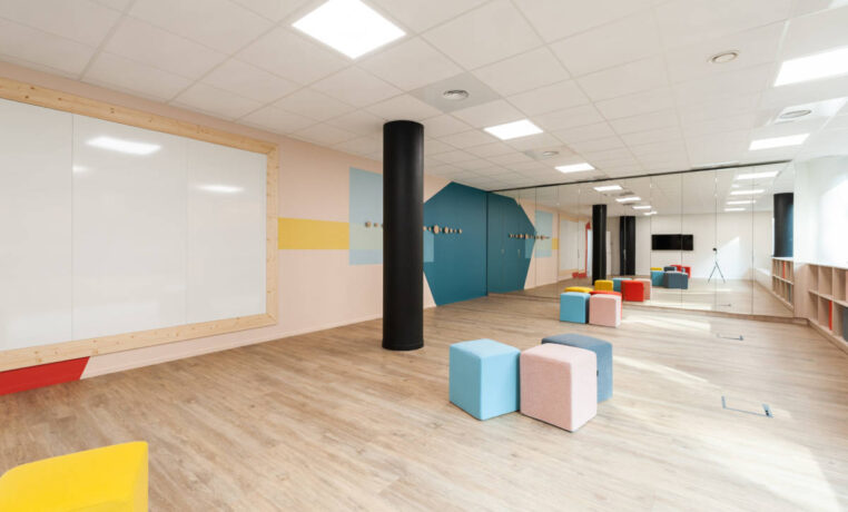 Salle de créativité aménagée avec des porte-manteaux Fixil, des poufs confortables et un tableau, offrant un espace inspirant et fonctionnel pour des sessions de brainstorming.