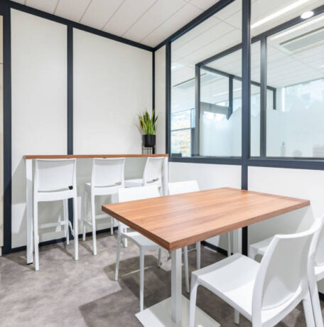 Cuisine chez Afyren aménagée avec une table en bois à piètement métal blanc et des chaises Maya blanches, combinant design épuré et fonctionnalité pour un espace de repas convivial.