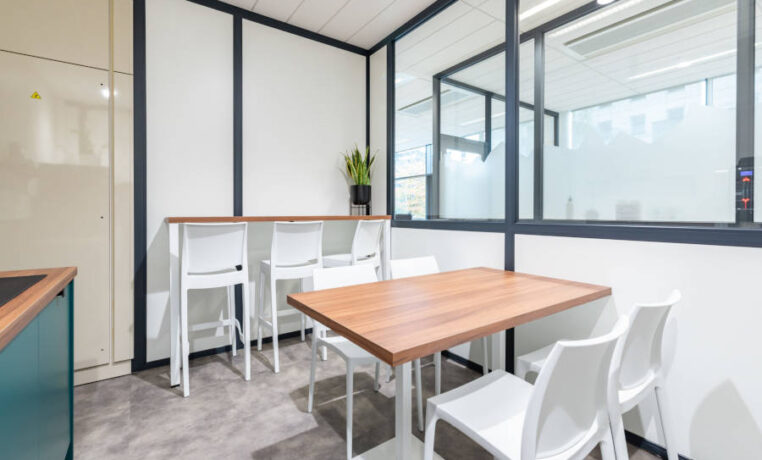 Cuisine chez Afyren aménagée avec une table en bois à piètement métal blanc et des chaises Maya blanches, combinant design épuré et fonctionnalité pour un espace de repas convivial.