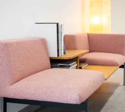 Deux fauteuils confortables disposés avec une table basse intégrée avec des magazines, créant un espace convivial et relaxant pour les pauses et les discussions informelles chez Techtera.