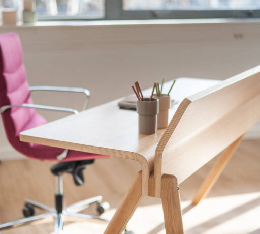 Bureau en bois élégant chez BOIRON accompagné d'un fauteuil en tissu rose, apportant une touche de couleur et de confort dans un espace de travail chic et fonctionnel.