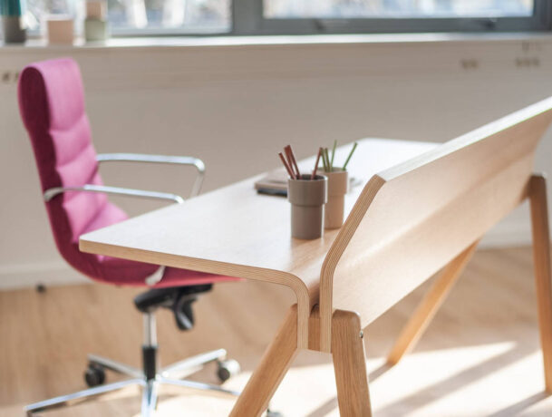 Bureau en bois élégant chez BOIRON accompagné d'un fauteuil en tissu rose, apportant une touche de couleur et de confort dans un espace de travail chic et fonctionnel.