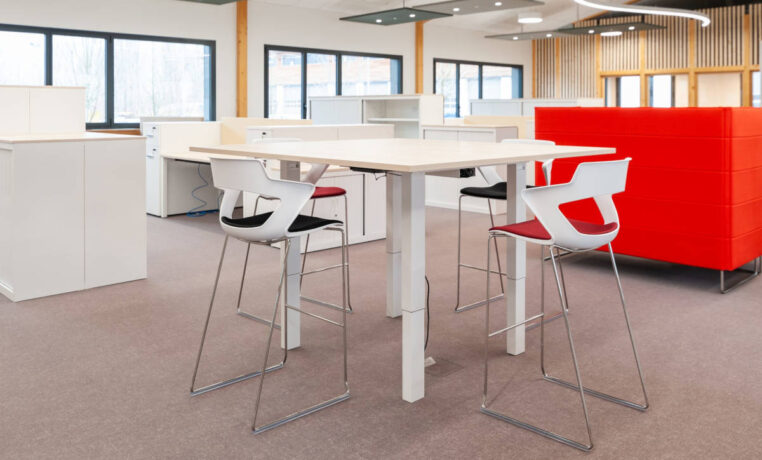Espace de pause avec une table haute et des tabourets Joky à piètement luge, offrant une configuration conviviale pour les repas et les échanges informels.
