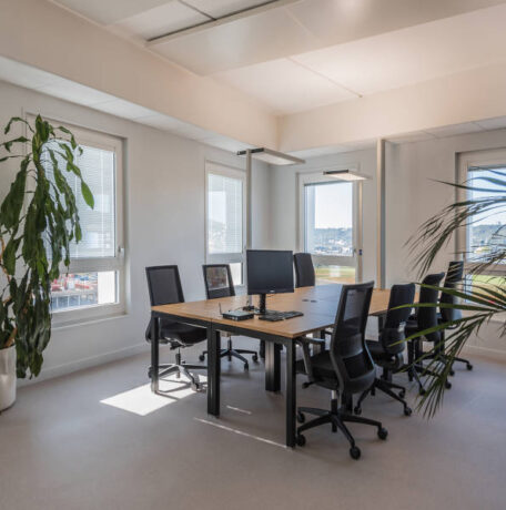 Salle de réunion chez Habitat 76, équipée de plusieurs tables U-DESK et de sièges ergonomiques, offrant un cadre professionnel pour les réunions et les présentations.