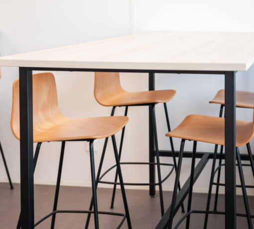 Table haute avec tabourets dans le réfectoire du Leader Mondial de Production de Transducteurs, offrant un espace moderne et pratique pour les repas rapides et les pauses café, tout en favorisant des interactions informelles entre collègues.