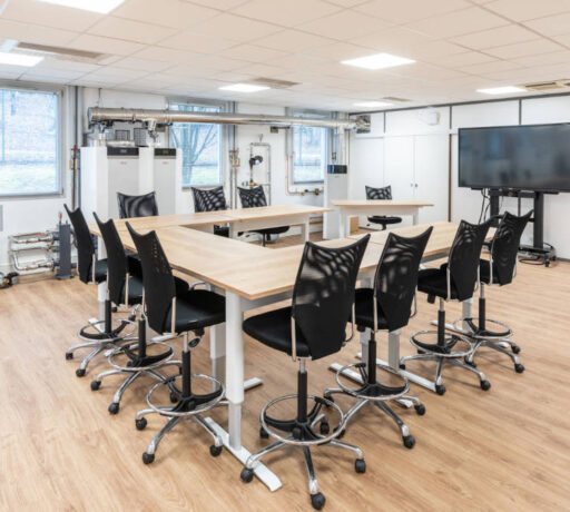 Zone de collaboration pour des formations chez Ariston, avec des tables réglables en hauteur et des sièges techniques ergonomiques, facilitant des configurations variées pour des réunions de groupe et des activités de collaboration.