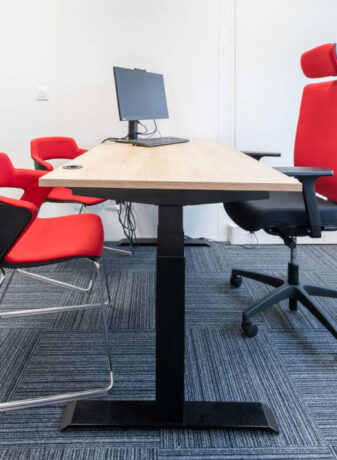 Bureau fermé chez Ariston équipé d'un bureau réglable en hauteur, d'un siège ergonomique et de chaises Joky à piètement luge, offrant un espace de travail privé et flexible.