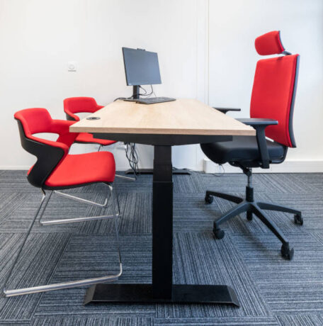 Bureau fermé chez Ariston équipé d'un bureau réglable en hauteur, d'un siège ergonomique et de chaises Joky à piètement luge, offrant un espace de travail privé et flexible.