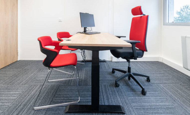Bureau fermé chez Ariston équipé d'un bureau réglable en hauteur, d'un siège ergonomique et de chaises Joky à piètement luge, offrant un espace de travail privé et flexible.