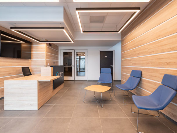 Banque d'accueil chez Carbogen Amcis, offrant un design moderne et fonctionnel pour accueillir les visiteurs avec un comptoir bien agencé et un espace d'attente confortable grâce aux fauteuils SILENCE.