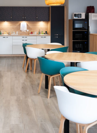 Coin cuisine au sein de Carbogen Amcis, équipé de tables contemporaines et de chaises confortables, créant un lieu idéal pour les pauses-café et les interactions sociales entre les collaborateurs.