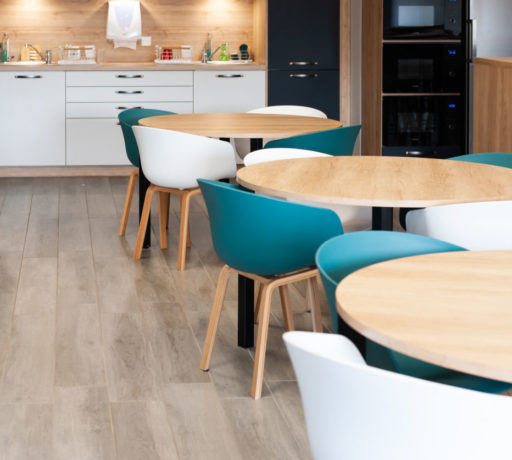 Coin cuisine au sein de Carbogen Amcis, équipé de tables contemporaines et de chaises confortables, créant un lieu idéal pour les pauses-café et les interactions sociales entre les collaborateurs.
