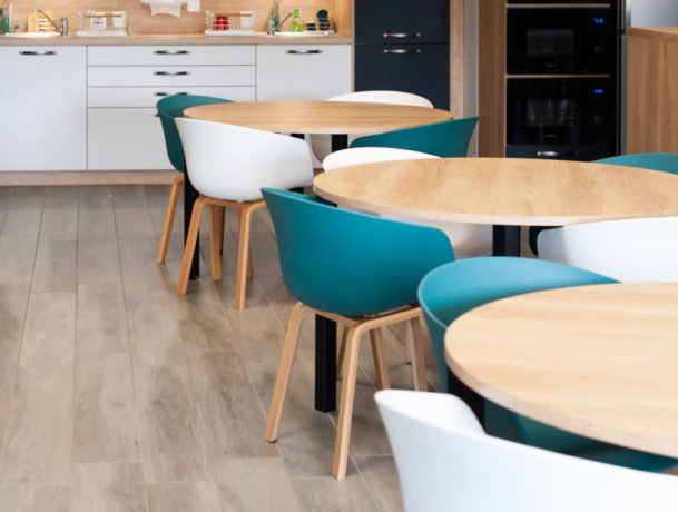 Coin cuisine au sein de Carbogen Amcis, équipé de tables contemporaines et de chaises confortables, créant un lieu idéal pour les pauses-café et les interactions sociales entre les collaborateurs.