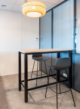 Espace de collaboration chez Carbogen Amcis, aménagé avec des tables hautes LINEA et des tabourets flexibles, conçu pour encourager les interactions créatives et le travail d'équipe.