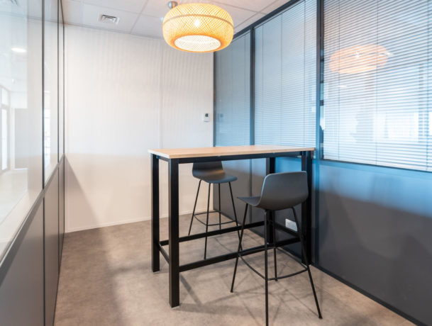 Espace de collaboration chez Carbogen Amcis, aménagé avec des tables hautes LINEA et des tabourets flexibles, conçu pour encourager les interactions créatives et le travail d'équipe.