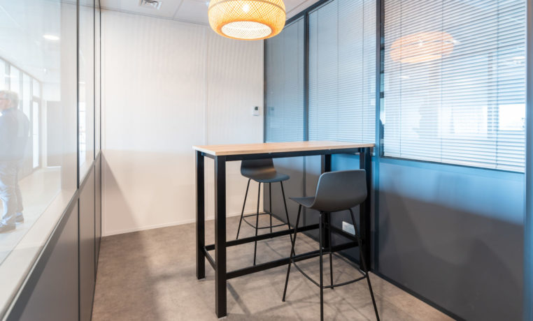 Espace de collaboration chez Carbogen Amcis, aménagé avec des tables hautes LINEA et des tabourets flexibles, conçu pour encourager les interactions créatives et le travail d'équipe.