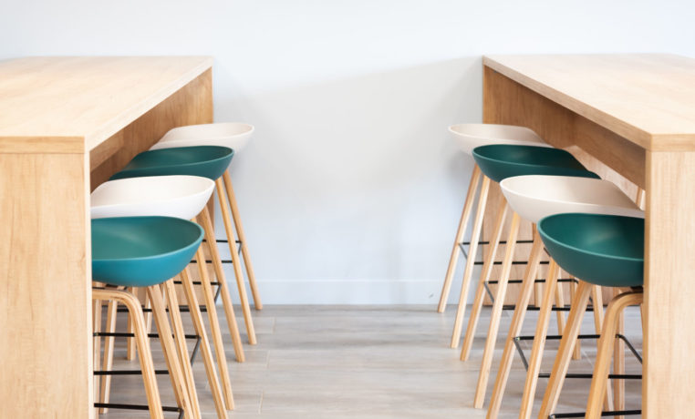 Réfectoire chez Carbogen Amcis, aménagé avec du mobilier moderne comprenant des tables haute SWARM et des tabourets élégantes aux couleurs de leur marque, offrant un espace convivial pour les pauses café et les repas informels.