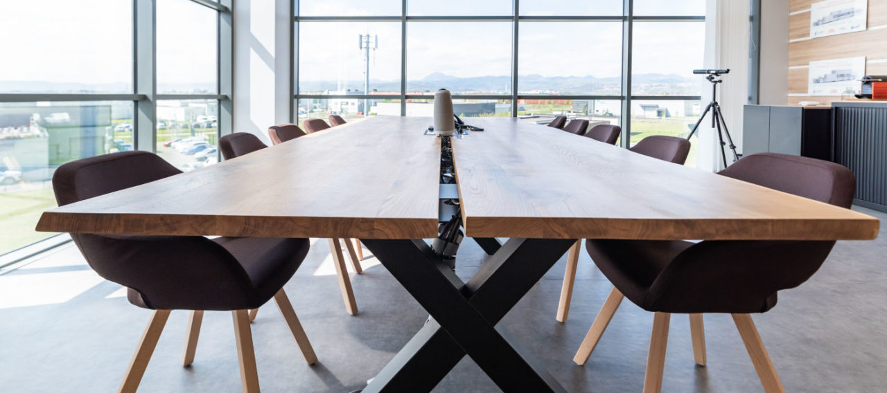 Salle de réunion lumineuse chez Carbogen Amcis, équipée d'une grande table en bois massif TIMBER entourée de fauteuils confortables, facilitant des réunions efficaces et des sessions de travail collaboratif.