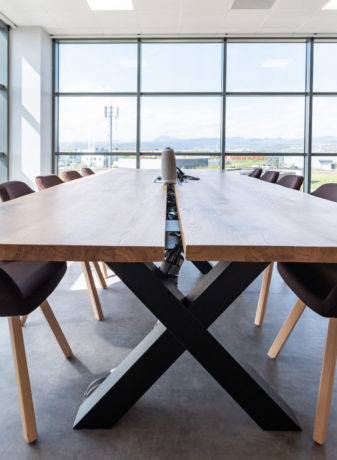 Salle de réunion lumineuse chez Carbogen Amcis, équipée d'une grande table en bois massif TIMBER entourée de fauteuils confortables, facilitant des réunions efficaces et des sessions de travail collaboratif.