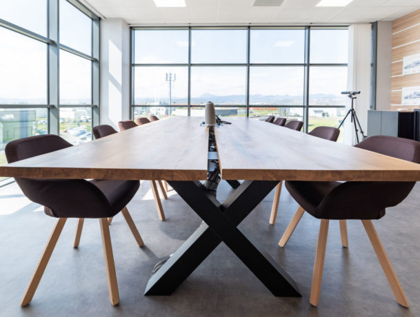 Salle de réunion lumineuse chez Carbogen Amcis, équipée d'une grande table en bois massif TIMBER entourée de fauteuils confortables, facilitant des réunions efficaces et des sessions de travail collaboratif.