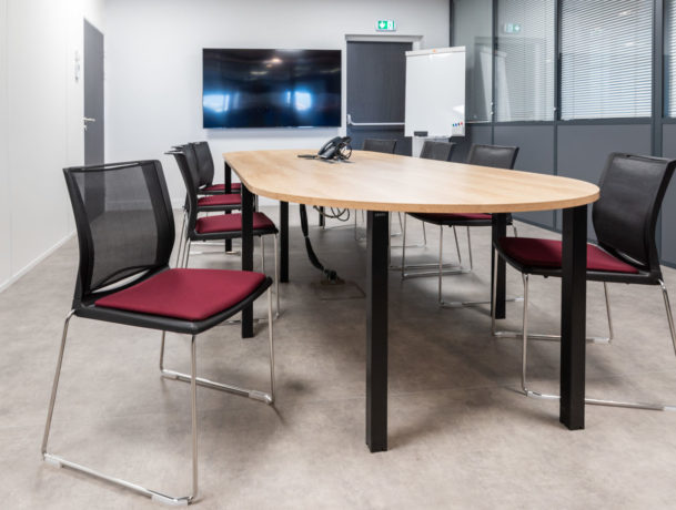 Salle de réunion chez Carbogen Amcis, dotée d'une grande table de conférence et de chaises confortables, offrant un cadre professionnel idéal pour des réunions importantes et des discussions en groupe.