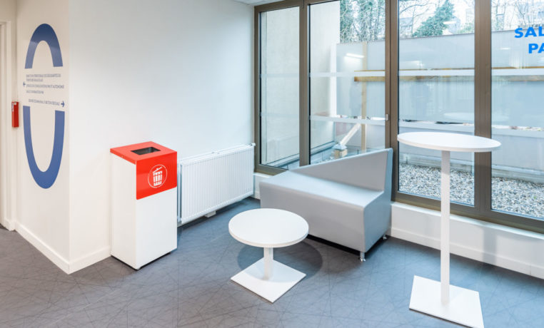Espace de pause chez Département du Rhône aménagé avec un canapé confortable, une table basse Linéa, une table haute Linéa et un container poubelle, idéal pour les moments d'attente.