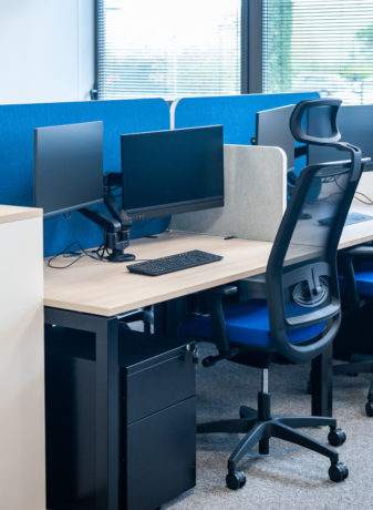 Open space avec des bureaux U-Desk séparés par des écrans acoustiques SILENS, complété par des caissons de rangement et un siège ergonomique, créant un environnement de travail moderne et fonctionnel.