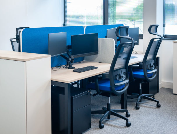 Open space avec des bureaux U-Desk séparés par des écrans acoustiques SILENS, complété par des caissons de rangement et un siège ergonomique, créant un environnement de travail moderne et fonctionnel.