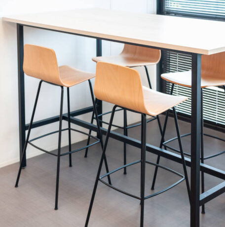 Table haute avec tabourets dans le réfectoire du Leader Mondial de Production de Transducteurs, offrant un espace moderne et pratique pour les repas rapides et les pauses café, tout en favorisant des interactions informelles entre collègues.