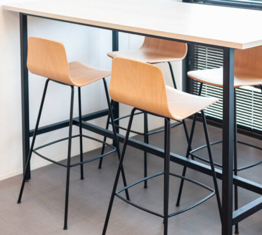 Table haute avec tabourets dans le réfectoire du Leader Mondial de Production de Transducteurs, offrant un espace moderne et pratique pour les repas rapides et les pauses café, tout en favorisant des interactions informelles entre collègues.