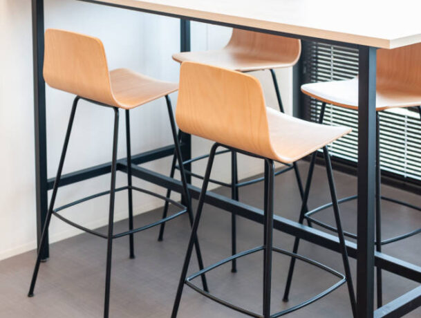 Table haute avec tabourets dans le réfectoire du Leader Mondial de Production de Transducteurs, offrant un espace moderne et pratique pour les repas rapides et les pauses café, tout en favorisant des interactions informelles entre collègues.