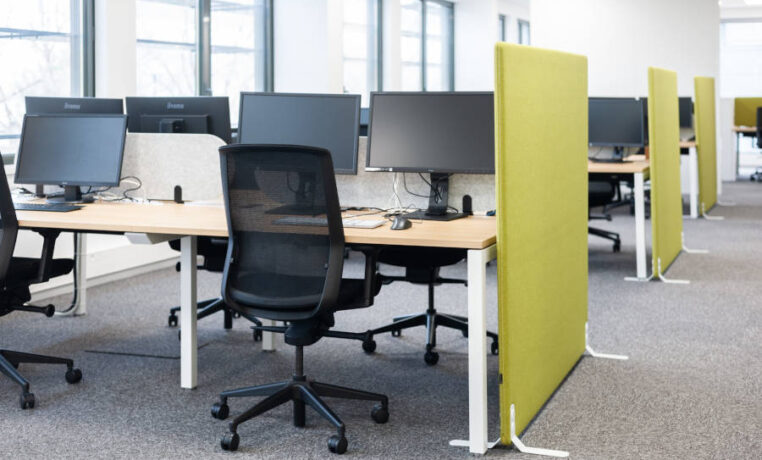 Open space Auvalie avec des bureaux U-Desk, des sièges ergonomiques et des séparateurs acoustiques sur pieds, créant un environnement de travail organisé et silencieux.