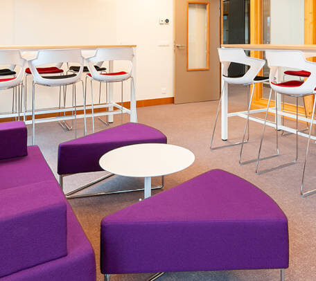 Espace détente à l'ATMB avec un canapé confortable et des tables basses, idéal pour prendre un encas ou se relaxer durant les pauses.
