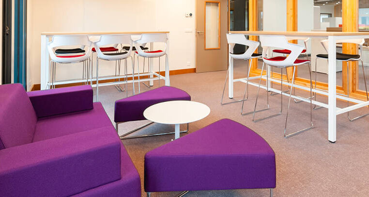 Espace détente à l'ATMB avec un canapé confortable et des tables basses, idéal pour prendre un encas ou se relaxer durant les pauses.