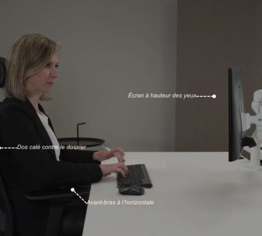 Personne assise correctement à son bureau : dos contre le dossier du siège, avant-bras formant un angle de 90° par rapport au corps, écran d'ordinateur placé droit devant les yeux à hauteur confortable.