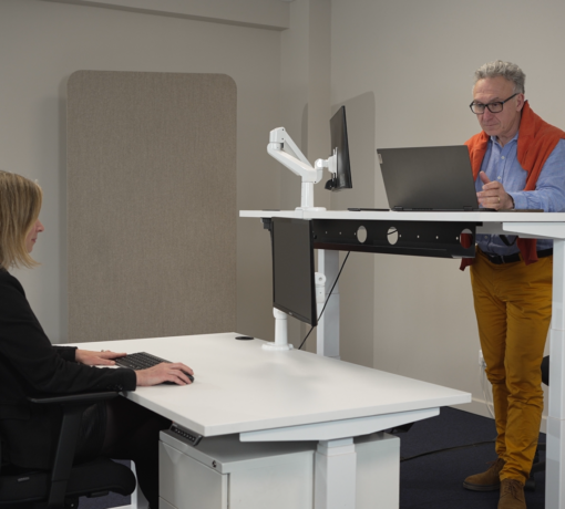 Aménagement ergonomique avec deux bureaux réglables en hauteur Dyna, illustrant les positions assise et debout au travail.