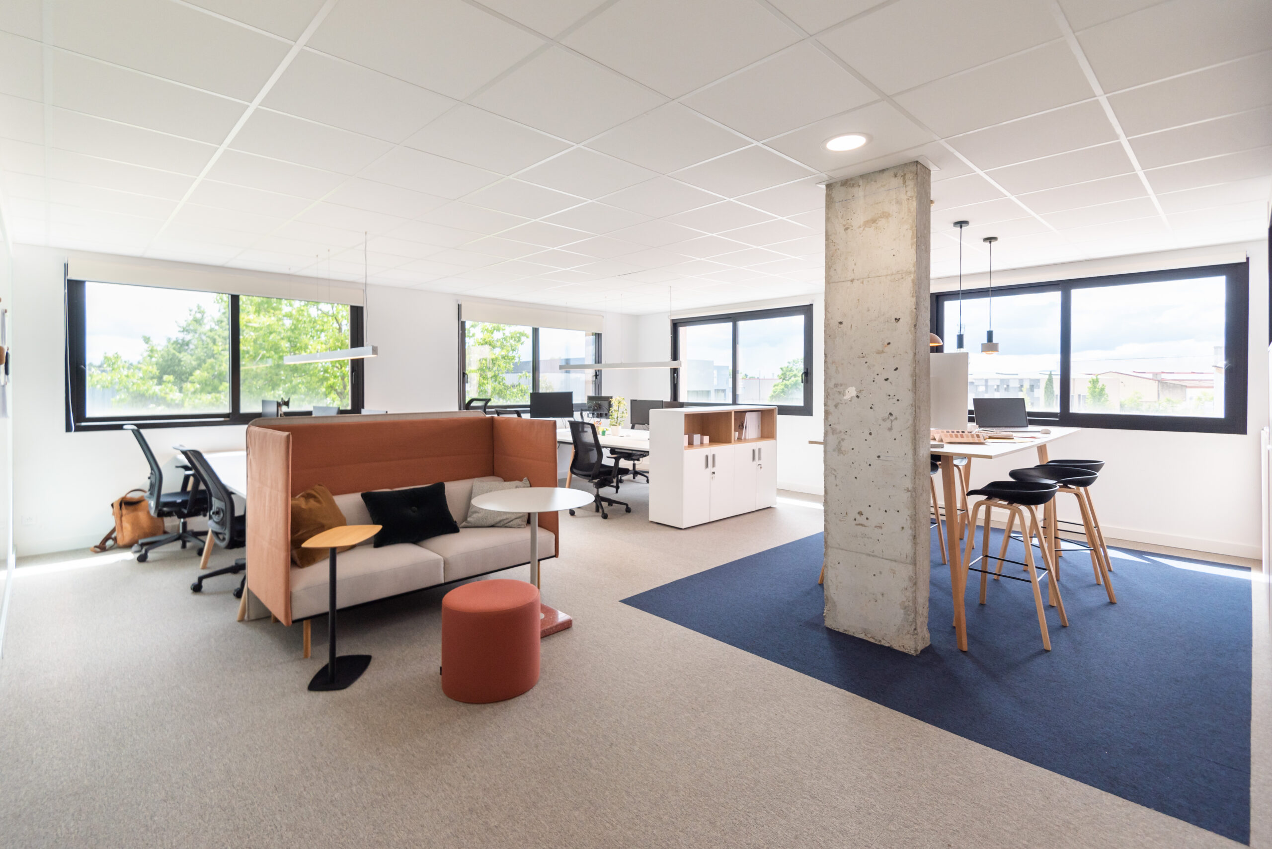 Open space avec table haute et canapé à l'agence Spark Office de Chassieu